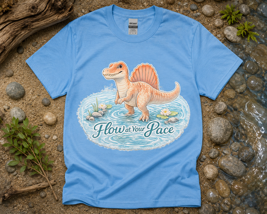 Flow at Your Pace Spinosaurus dinosaur shirt flatlay on Carolina Blue Gildan 5000 peaceful dinosaur graphic tee USA