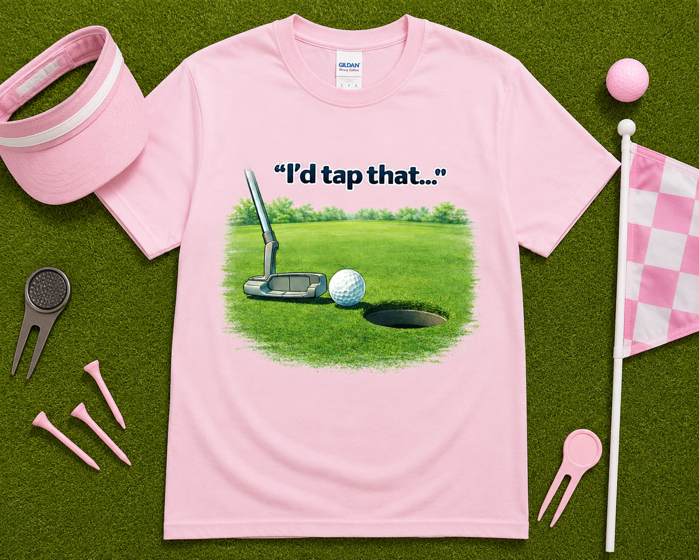 Light pink golf graphic t shirt flatlay with I'd Tap That putting design and golf accessories, fun golf gift shirt for women golfers and golf enthusiasts.