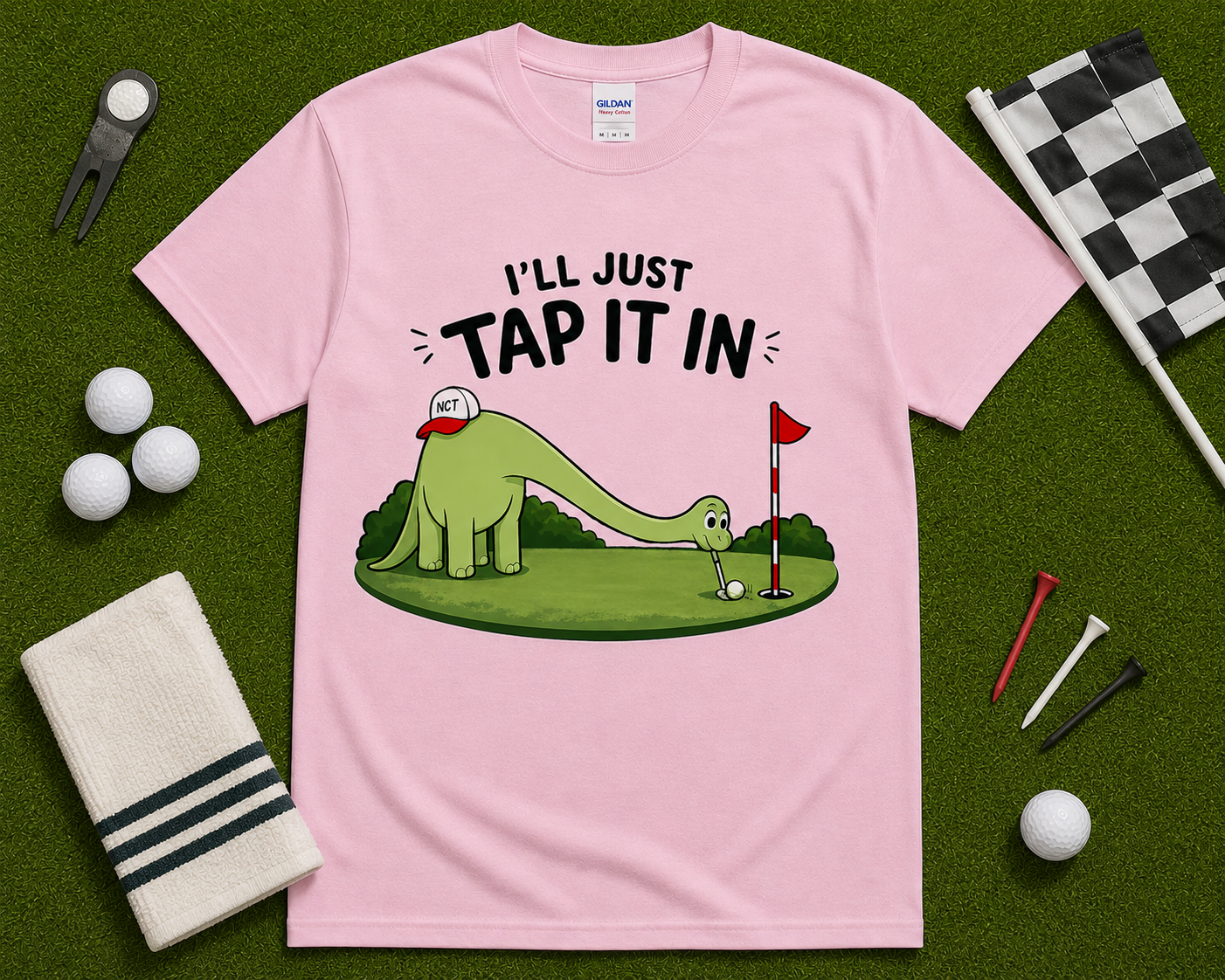 Light Pink golf dinosaur shirt flatlay with Ill Just Tap It In funny brontosaurus golfer graphic on golf themed grass background cute golf gift USA