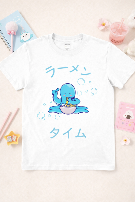 White graphic t-shirt featuring kawaii octopus eating ramen with Japanese text and bubbles, styled in a pastel flatlay with cute accessories and soft aesthetic props