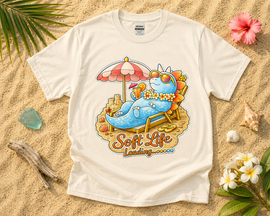 Soft Life Stegosaurus dinosaur graphic tee on natural Gildan shirt with beach sand tropical vacation flatlay cozy summer aesthetic