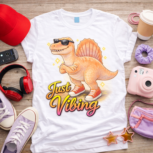 Just Vibing spinosaurus graphic tee on white shirt with sunglasses sneakers and colorful gradient text cute dinosaur shirt