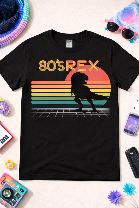 Black dinosaur graphic tee with retro 80s T-Rex design, neon sunset, and synthwave grid, styled in a vibrant flat lay with colorful accessories