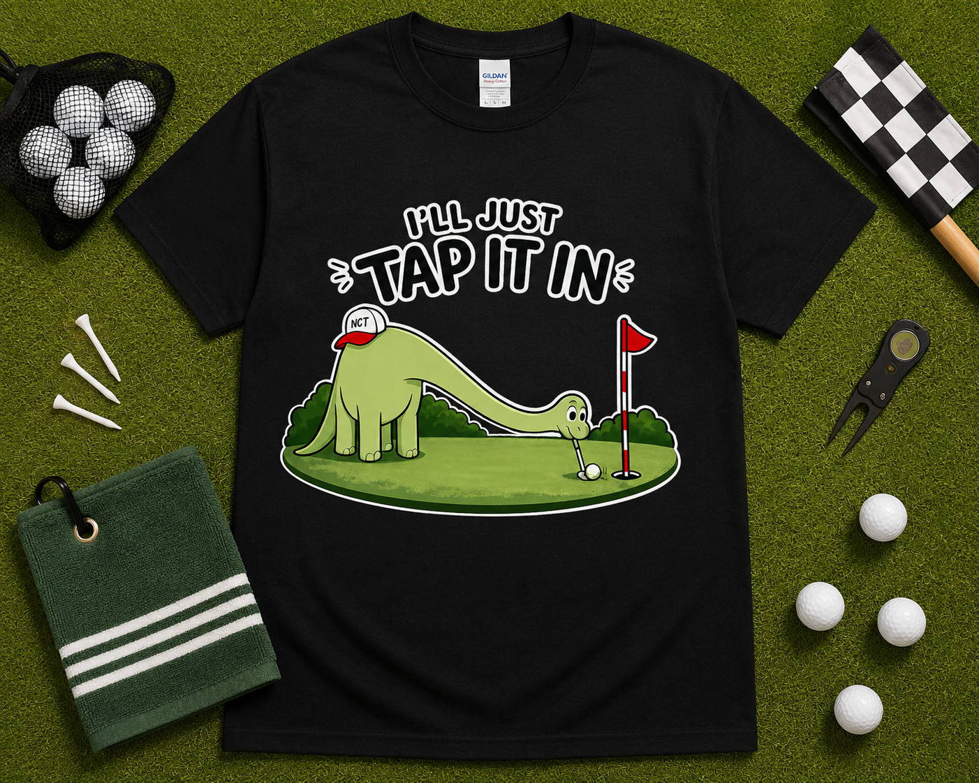 Black funny golf dinosaur shirt flatlay featuring Ill Just Tap It In brontosaurus golfer design on golf themed grass background golf gift for men women and youth USA