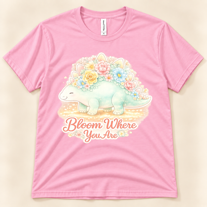 Bloom Where You Are Stegosaurus graphic tee in Pink featuring a cute floral stegosaurus and positive inspirational saying from New Chapter Tees, a California small business.