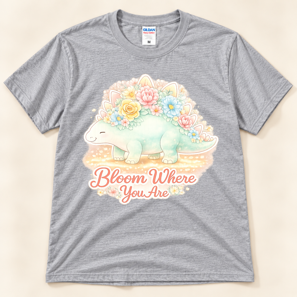 Bloom Where You Are Stegosaurus graphic tee in Sport Gray featuring a cute pastel stegosaurus covered in colorful flowers from New Chapter Tees, a California small business.