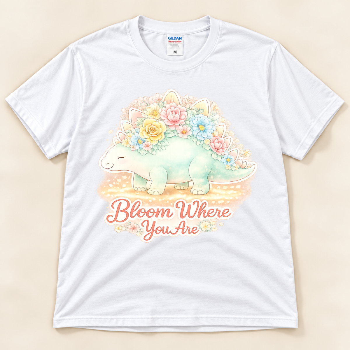 Bloom Where You Are Stegosaurus graphic tee in White featuring a pastel floral dinosaur and uplifting Bloom Where You Are quote from New Chapter Tees, a California small business.