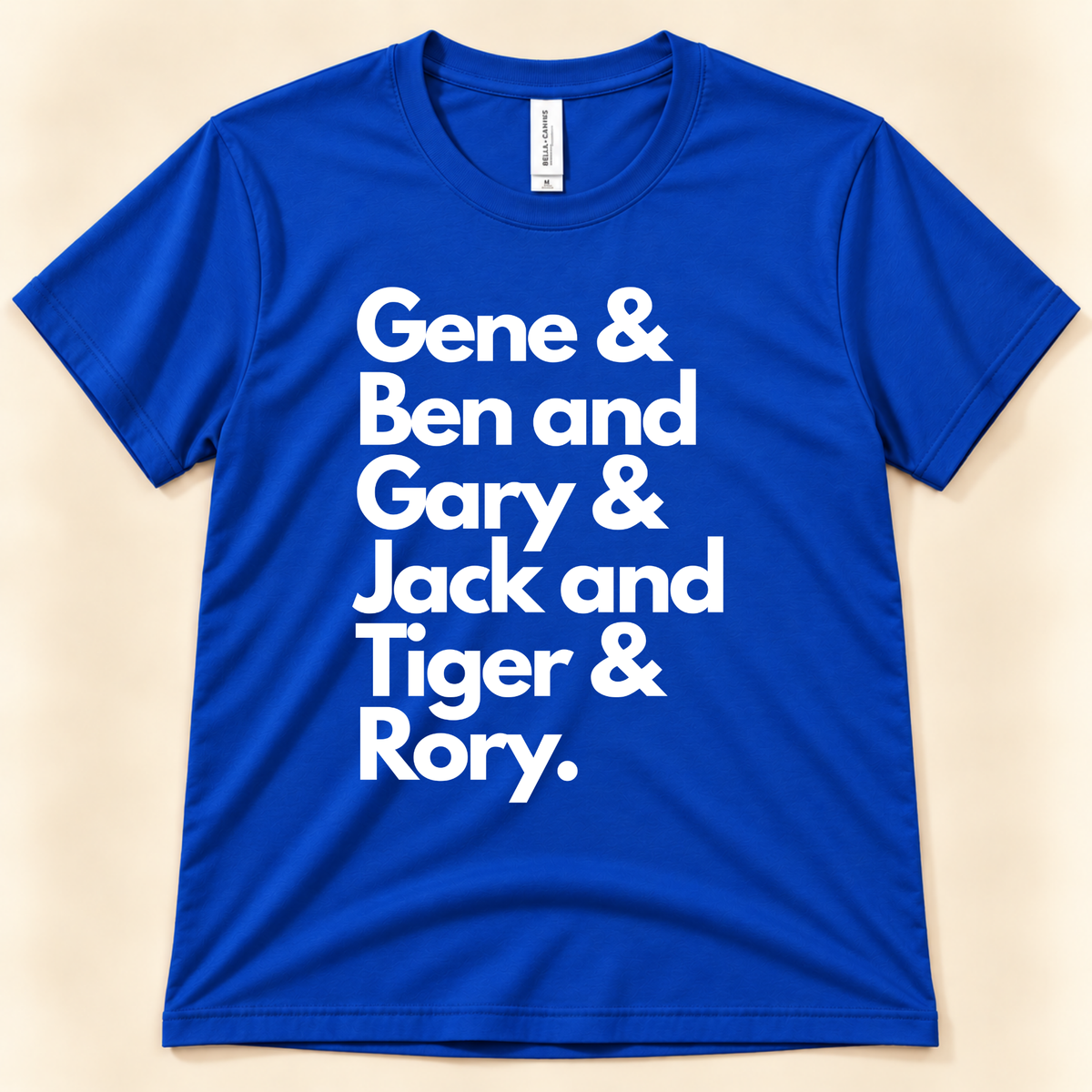 True Royal blue Bella Canvas 3001 golf graphic tee featuring bold white lettering with the first names of six men's career Grand Slam winners, from New Chapter Tees, a California small business.