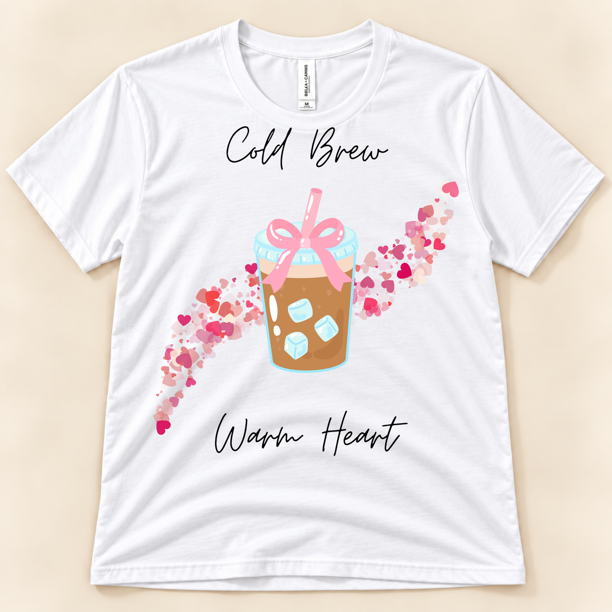 White Bella Canvas 3001 coffee lover tee featuring a cold brew cup with pink bow and colorful heart trail.