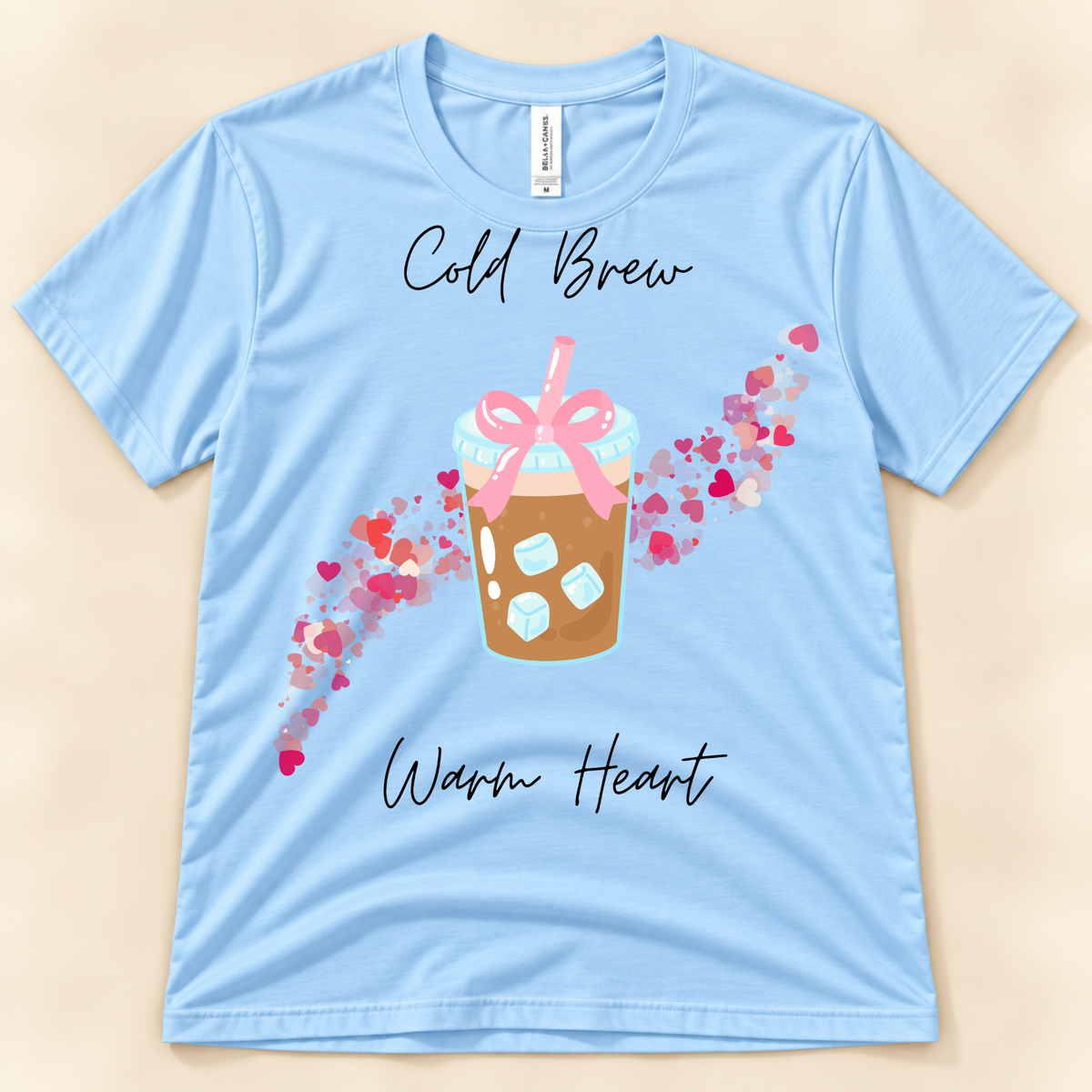 Baby Blue Bella Canvas 3001 iced coffee tee with a cold brew cup, pink bow and colorful heart trail.
