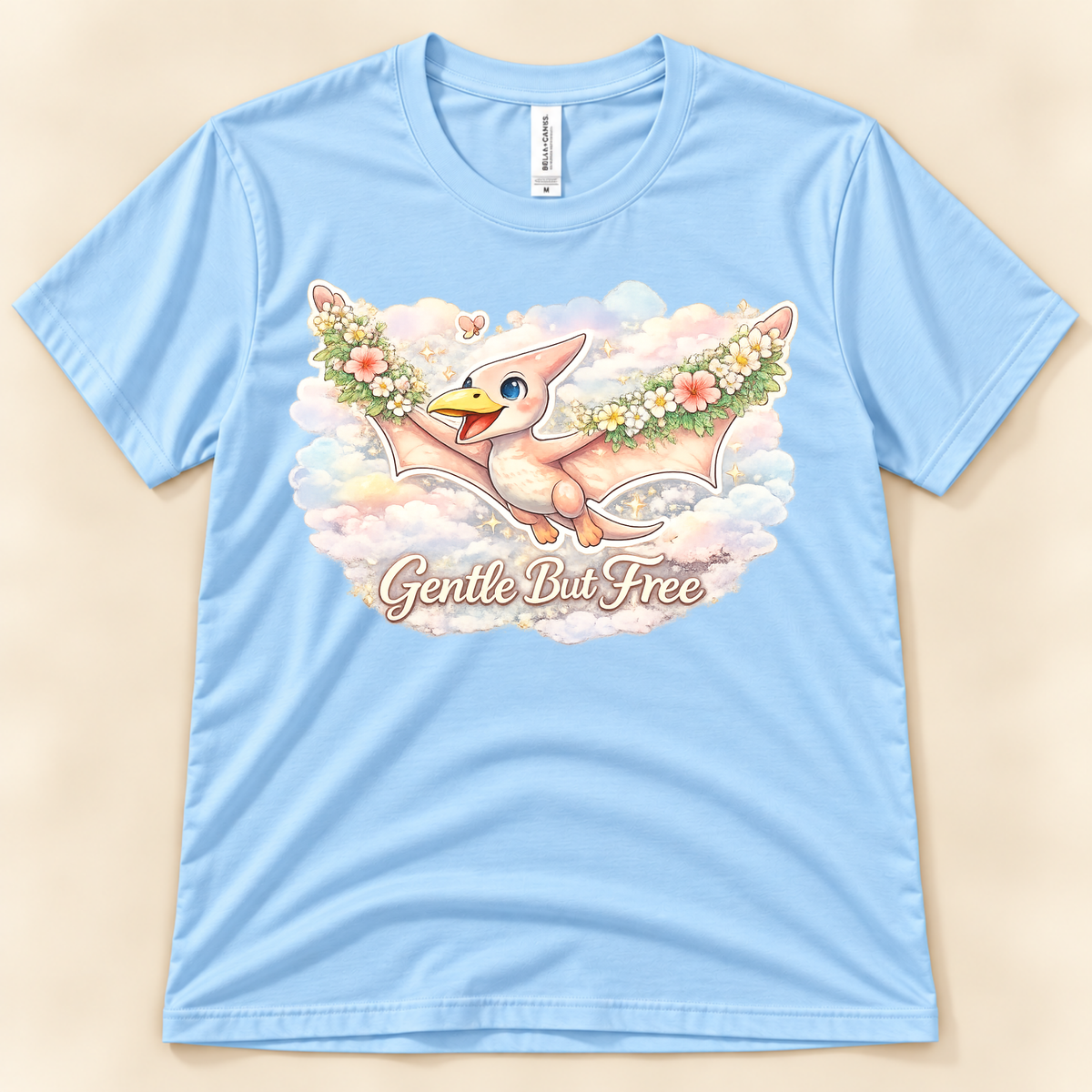 Gentle But Free pterodactyl graphic tee in Baby Blue featuring a floral flying dinosaur and dreamy clouds from New Chapter Tees, a California small business.