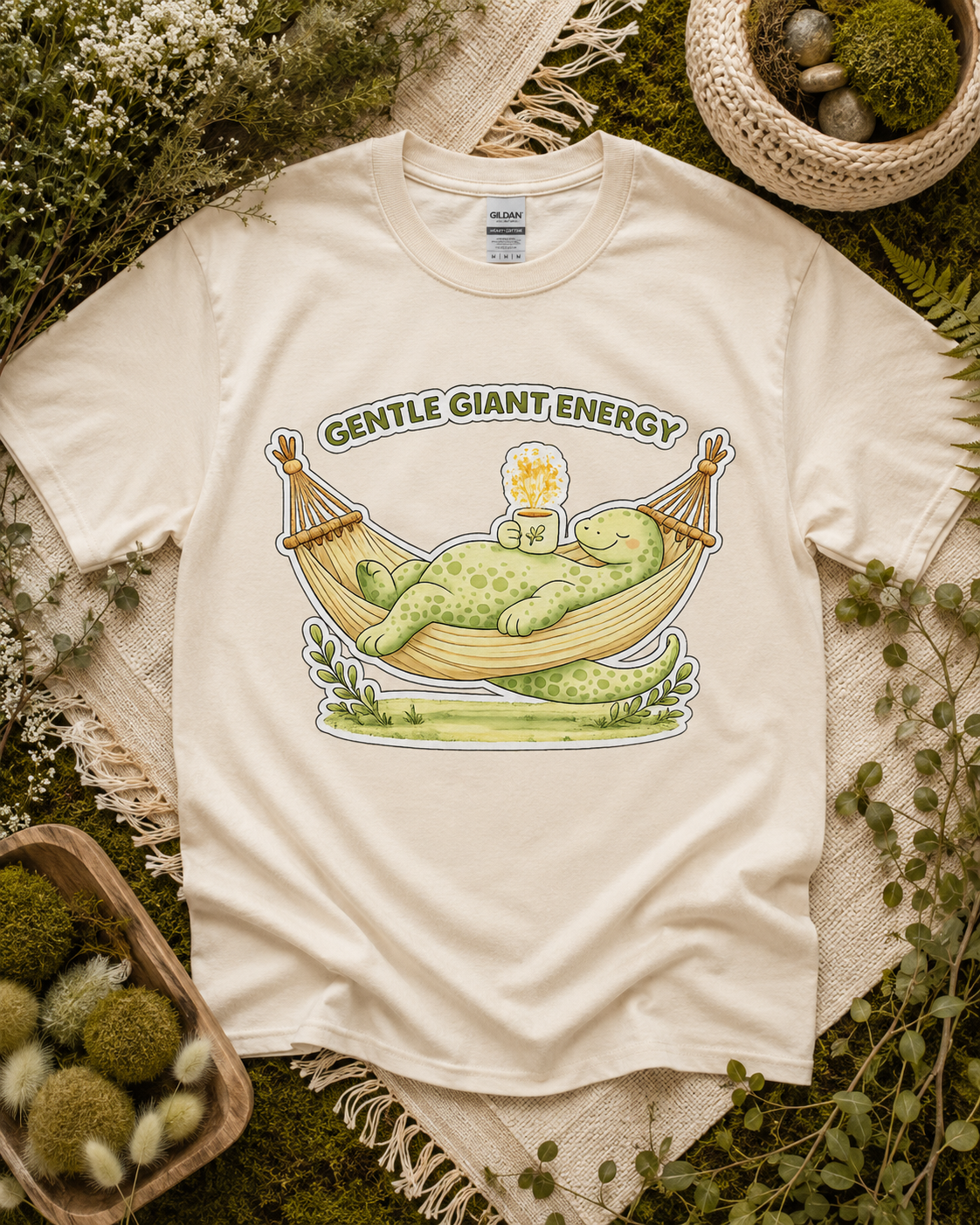 Gentle Giant Energy dinosaur shirt on Natural Gildan Heavy Cotton with peaceful dinosaur hammock artwork inspired by slow living and cozy nature vibes.
