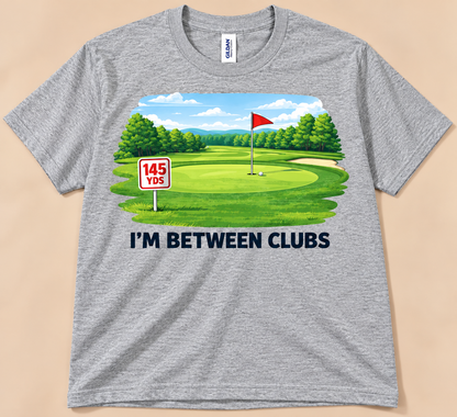 Sport Gray Gildan 5000 I’m Between Clubs Tee with colorful golf course, 145 yard marker and golfer humor