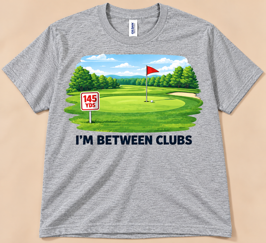 Sport Gray Gildan 5000 I’m Between Clubs Tee with colorful golf course, 145 yard marker and golfer humor