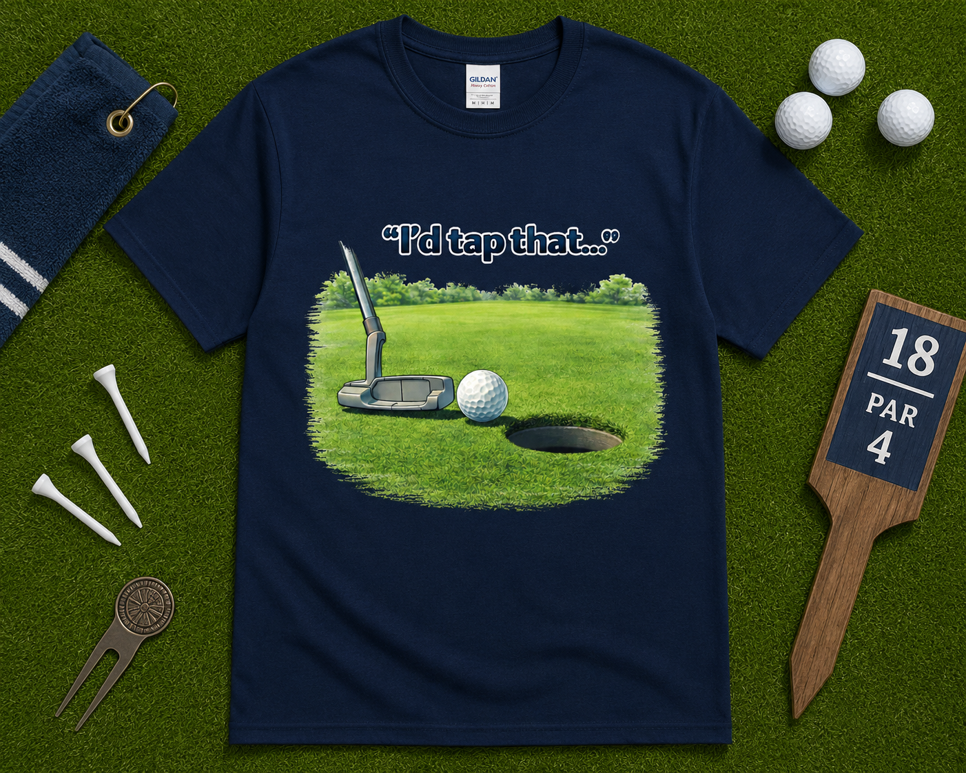 Navy blue golf graphic t shirt flatlay featuring I'd Tap That putting design with golf themed accessories, funny golf gift shirt for golfers across the United States.