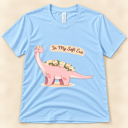 Baby Blue Bella Canvas 3001 In My Soft Era dinosaur tee featuring a cute pink Brontosaurus with floral details and soft life artwork from New Chapter Tees, a California small business.