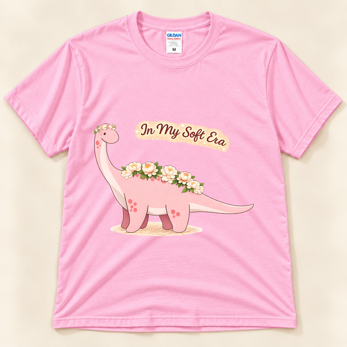 Light Pink Gildan 5000 In My Soft Era dinosaur tee featuring a cute pink Brontosaurus with floral details and a cozy soft life theme from New Chapter Tees, a California small business.