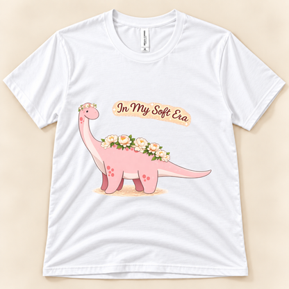 White Bella Canvas 3001 In My Soft Era dinosaur graphic tee featuring a cute pink floral Brontosaurus and soft life saying from New Chapter Tees, a California small business.