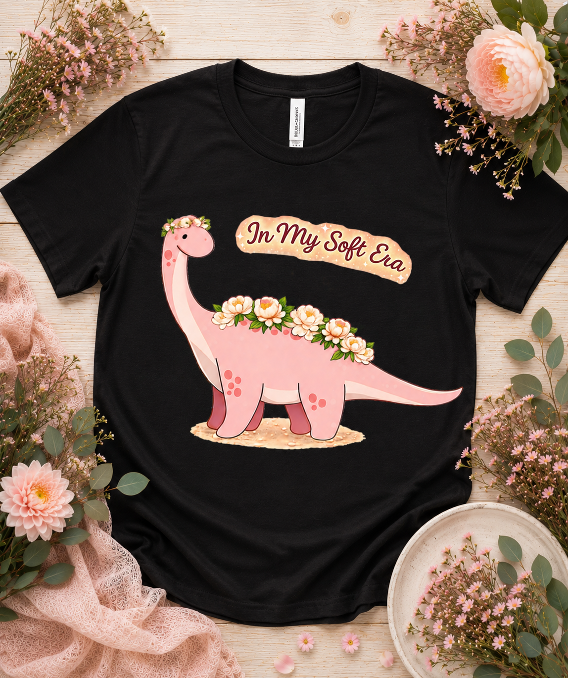 Bella Canvas 3001 black dinosaur graphic tee featuring pink floral In My Soft Era dinosaur artwork bold cute aesthetic premium shirt for women