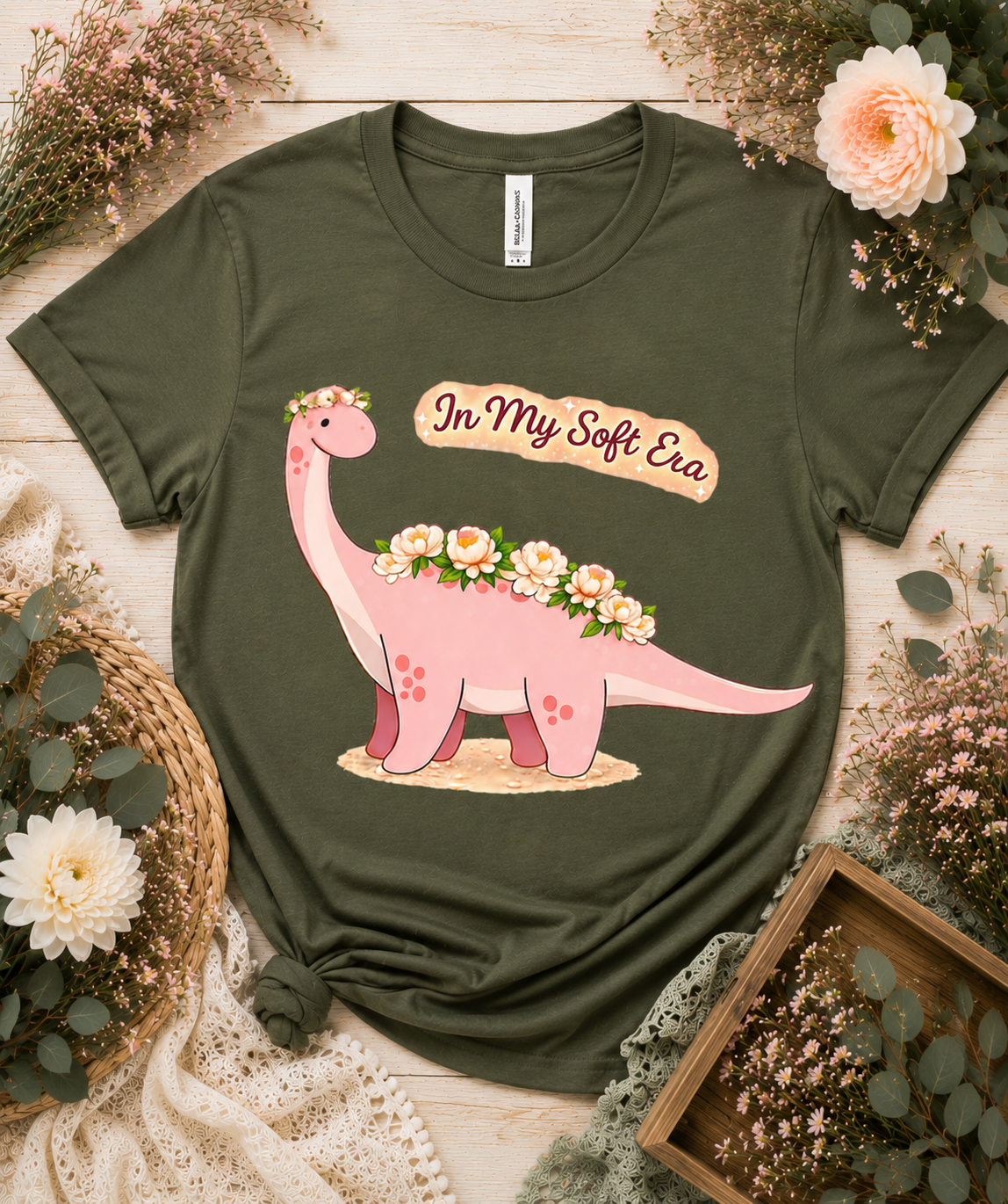 Bella Canvas 3001 military green dinosaur graphic tee featuring In My Soft Era pink floral dinosaur artwork unique aesthetic gift for dinosaur lovers