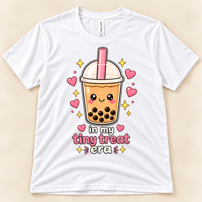 White Bella Canvas 3001 kawaii boba graphic tee featuring a smiling bubble milk tea cup with tapioca pearls, pink hearts, golden sparkles, and In My Tiny Treat Era lettering from New Chapter Tees, a California small business.