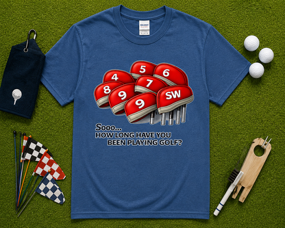 Indigo Blue golf graphic tee flatlay featuring funny How Long Have You Been Playing Golf design with golf club headcovers and golf themed accessories. Humorous golf shirt for golfers, golf lovers, country club members, tournament players, and golf gift shoppers in California, Florida, Arizona, Texas, and throughout the USA.