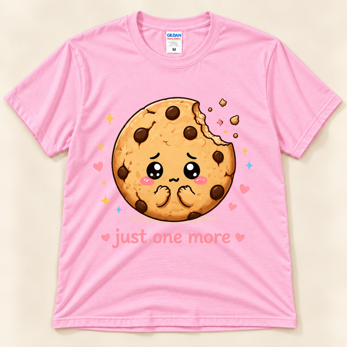 Light Pink Gildan 5000 Just One More Cookie tee featuring a cute chocolate chip cookie character with big eyes, colorful hearts and sparkles from New Chapter Tees, a California small business.