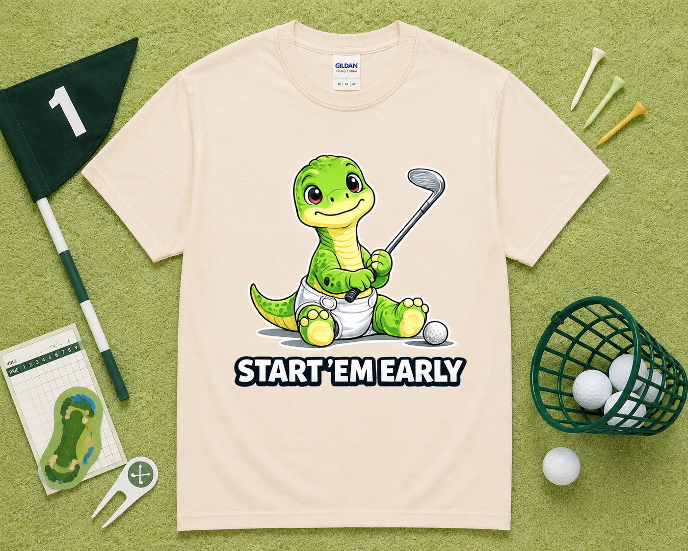 Natural Gildan 5000 cute dinosaur golf shirt flatlay with golf accessories on light green grass, funny Start Em Early golf tee gift for golfers, children and golf enthusiasts in the USA.