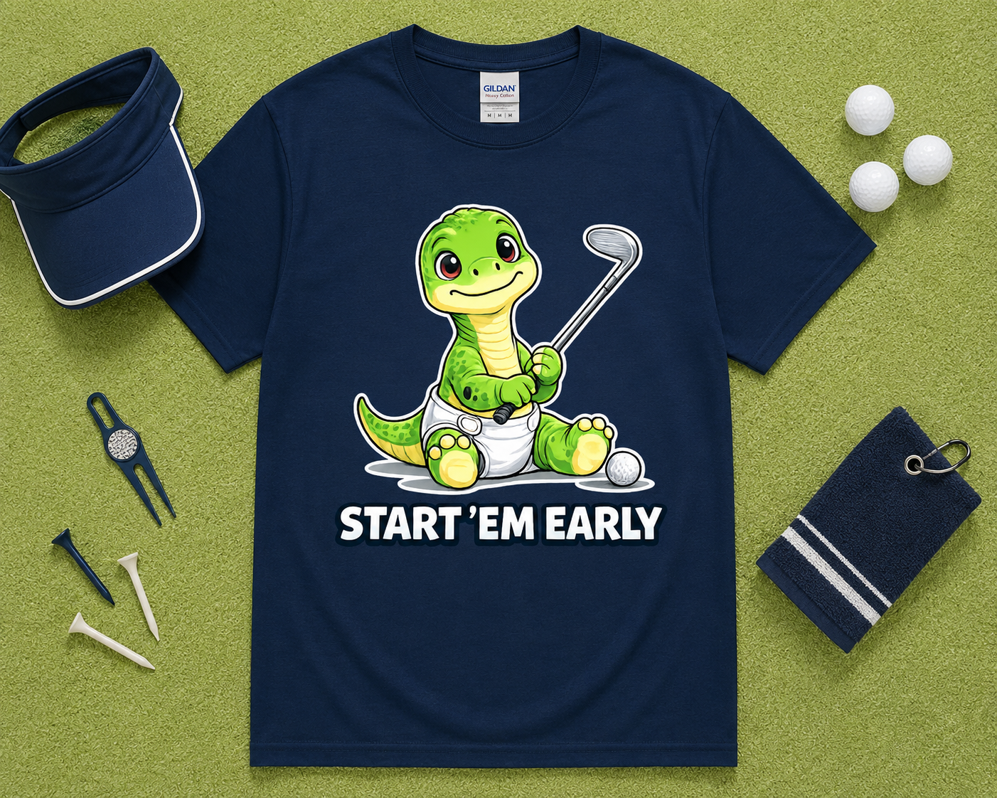 Navy Gildan 5000 funny dinosaur golf shirt flatlay with golf accessories on light green grass, cute Start Em Early golf tee gift for golfers, dads, kids and golf families in the USA.