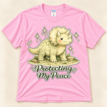Light Pink Gildan 5000 Protecting My Peace dinosaur shirt featuring a cute Triceratops with an encouraging peace and self care message from New Chapter Tees, a California small business.