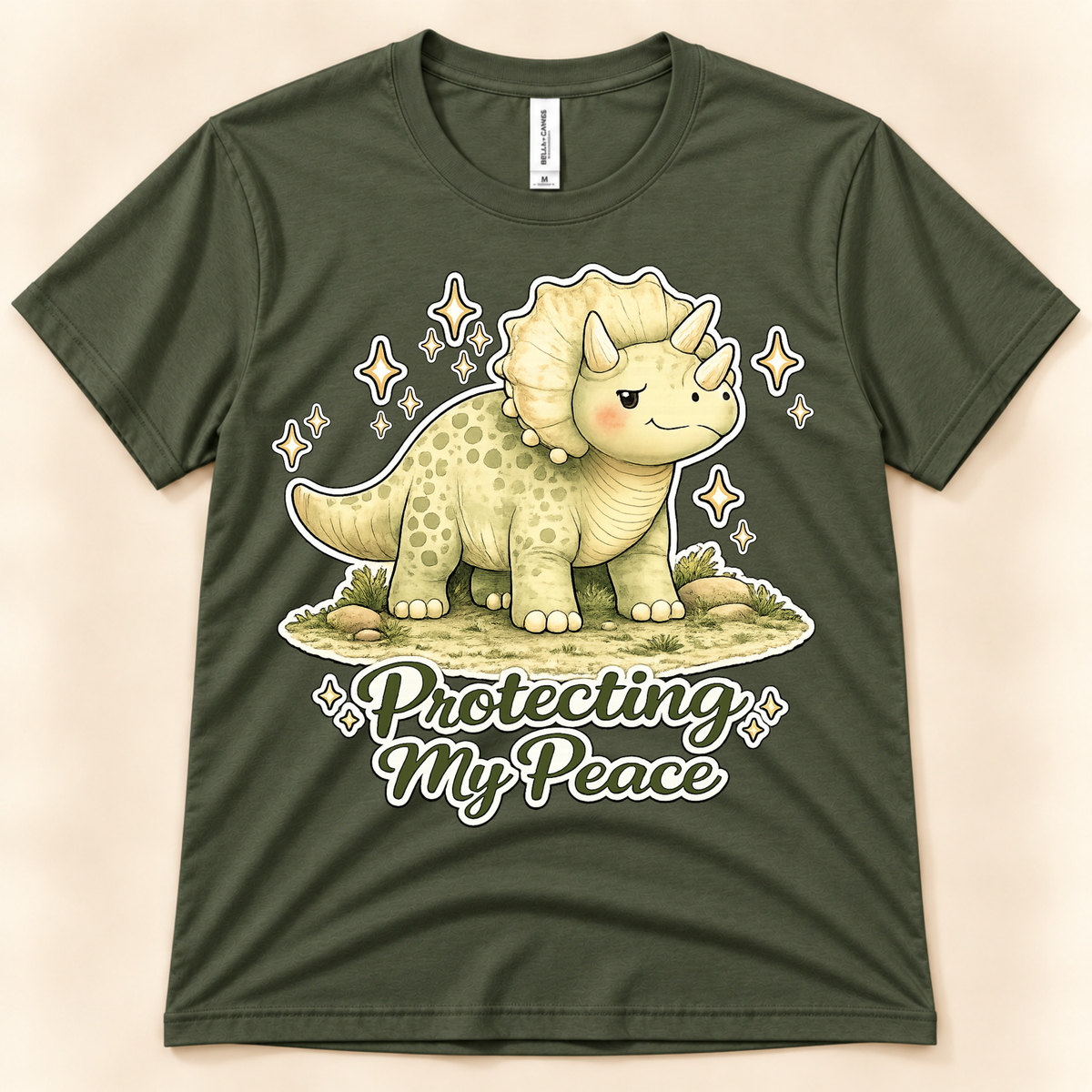 Military Green Bella Canvas 3001 Protecting My Peace dinosaur shirt featuring a cute Triceratops, sparkling accents and peaceful self care message from New Chapter Tees, a California small business.