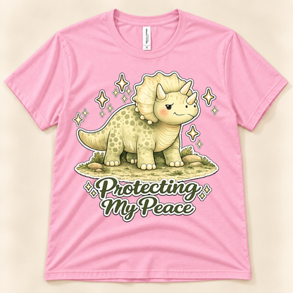 Pink Bella Canvas 3001 Protecting My Peace graphic tee featuring a cute Triceratops with a positive peace and self care message from New Chapter Tees, a California small business.