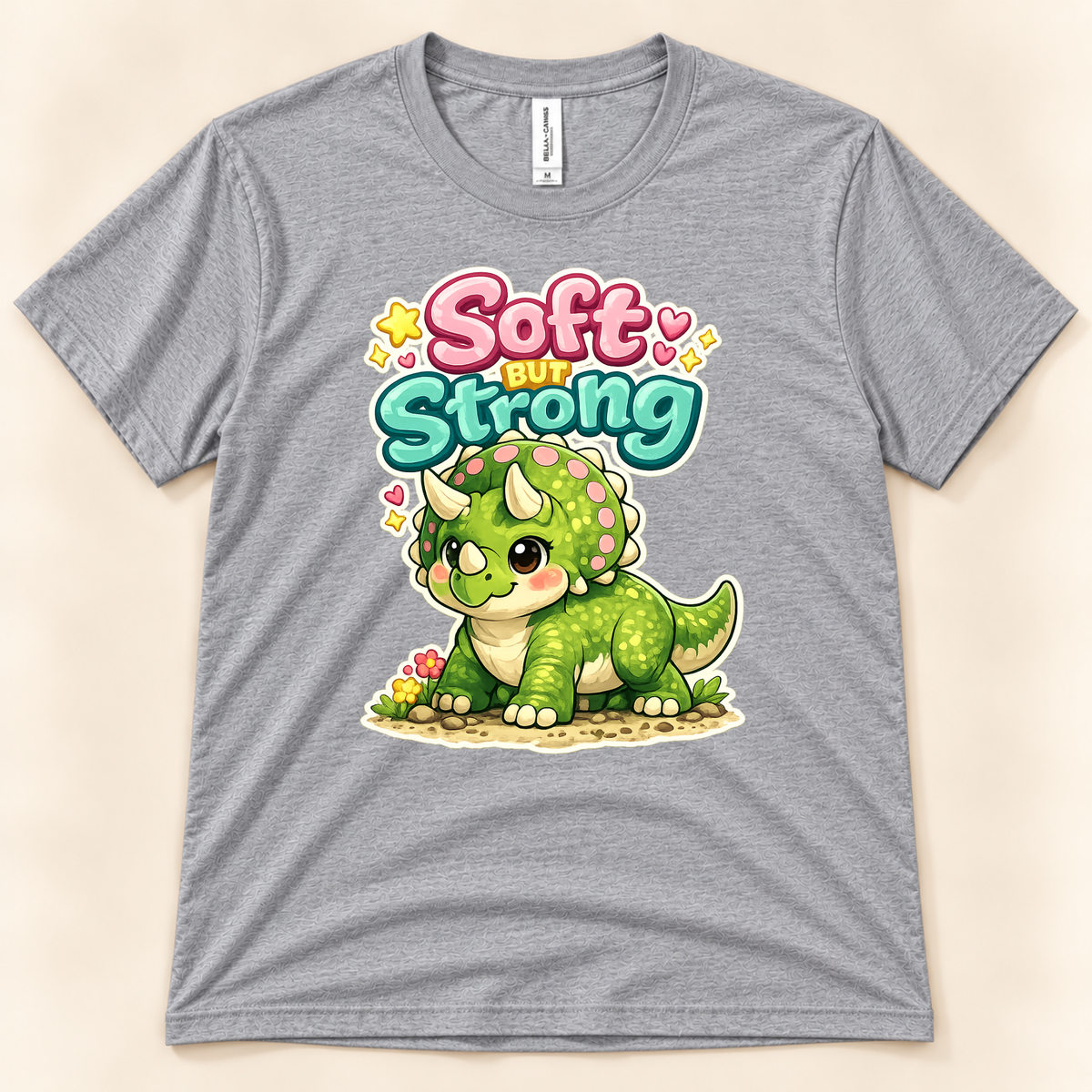 Soft But Strong cute triceratops graphic tee in Athletic Heather by New Chapter Tees, a California small business, with colorful dinosaur artwork.
