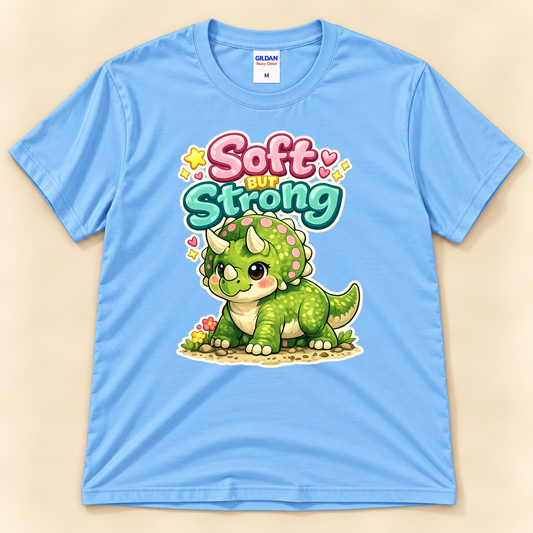 Soft But Strong triceratops graphic tee in Carolina Blue by New Chapter Tees, a California small business, featuring colorful cute dinosaur artwork.