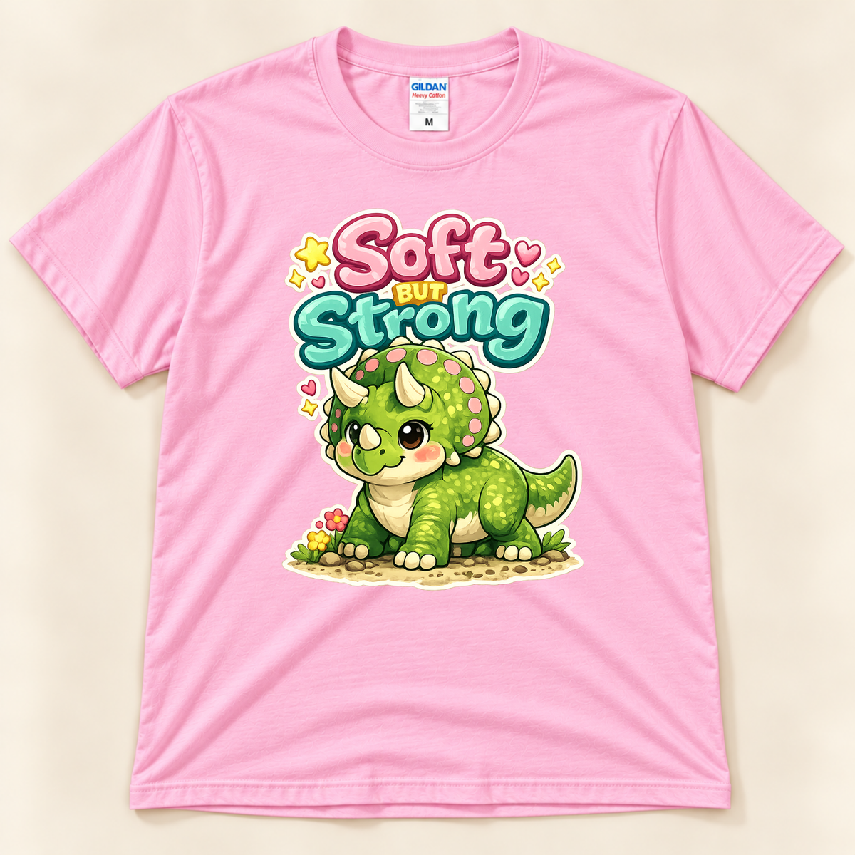 Soft But Strong cute triceratops graphic tee in Light Pink by New Chapter Tees, a California small business, with colorful kawaii dinosaur artwork.