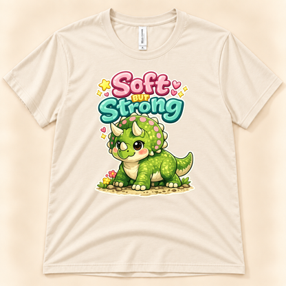 Soft But Strong triceratops graphic tee in Natural by New Chapter Tees, a California small business, with a cute green dinosaur and colorful lettering.