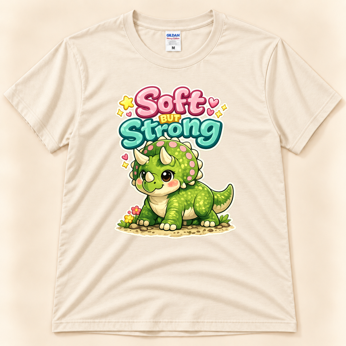 Soft But Strong triceratops graphic tee in Natural by New Chapter Tees, a California small business, featuring a cute green dinosaur design.