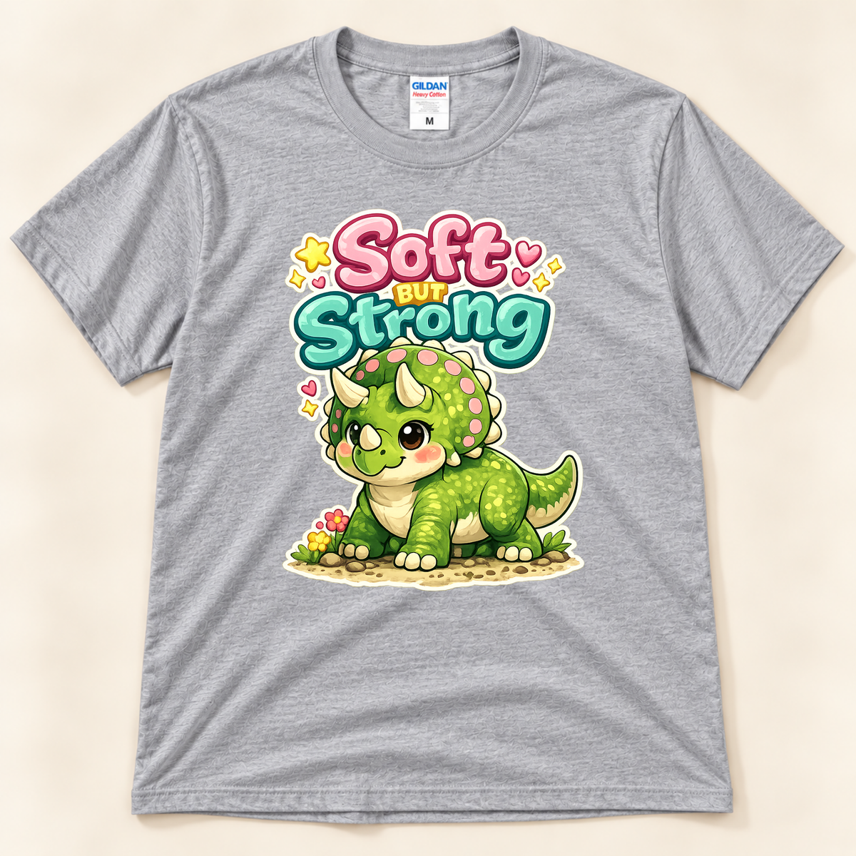 Soft But Strong cute dinosaur graphic tee in Sport Gray by New Chapter Tees, a California small business, featuring a colorful green triceratops design.