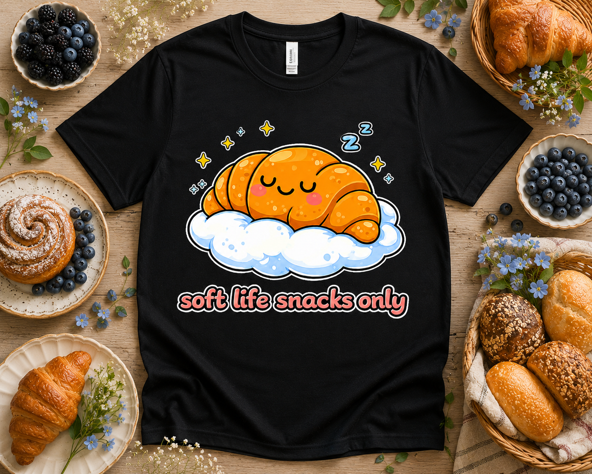 Black Bella Canvas 3001 Soft Life Snacks Only croissant graphic tee flatlay with bakery props