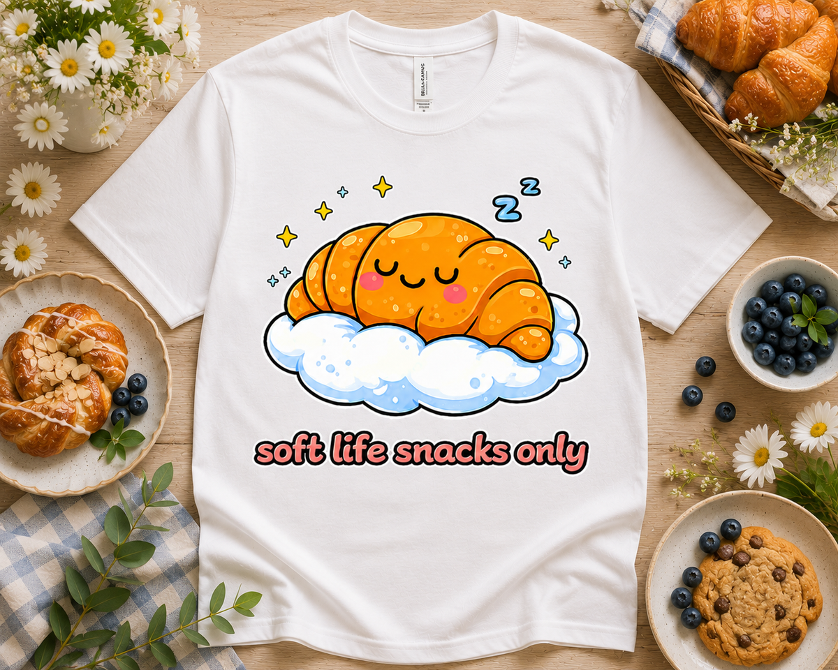 White Bella Canvas 3001 Soft Life Snacks Only croissant graphic tee cozy bakery themed flatlay
