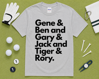 Sport Gray Gildan 5000 funny golf shirt flatlay featuring Gene Ben Gary Jack Tiger Rory graphic with golf accessories on light green grass, golfer gift idea, unisex golf clothing for golfers across the USA.
