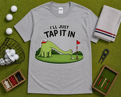 Sport Gray funny golf shirt flatlay featuring Ill Just Tap It In dinosaur golfer graphic on golf themed grass background comfortable golf lover gift USA