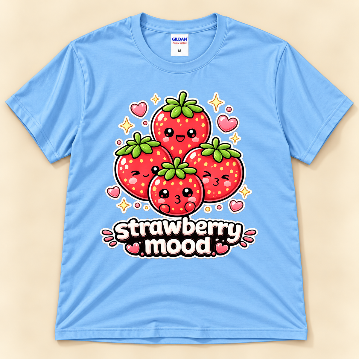 Carolina Blue Gildan 5000 kawaii fruit graphic tee featuring four adorable cartoon strawberries with cheerful expressions, hearts, sparkles, and Strawberry Mood lettering from New Chapter Tees, a California small business.