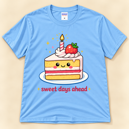 Carolina Blue Gildan 5000 kawaii cake graphic shirt featuring a happy strawberry cake slice, lit birthday candle, pink frosting, and Sweet Days Ahead lettering from New Chapter Tees, a California small business.