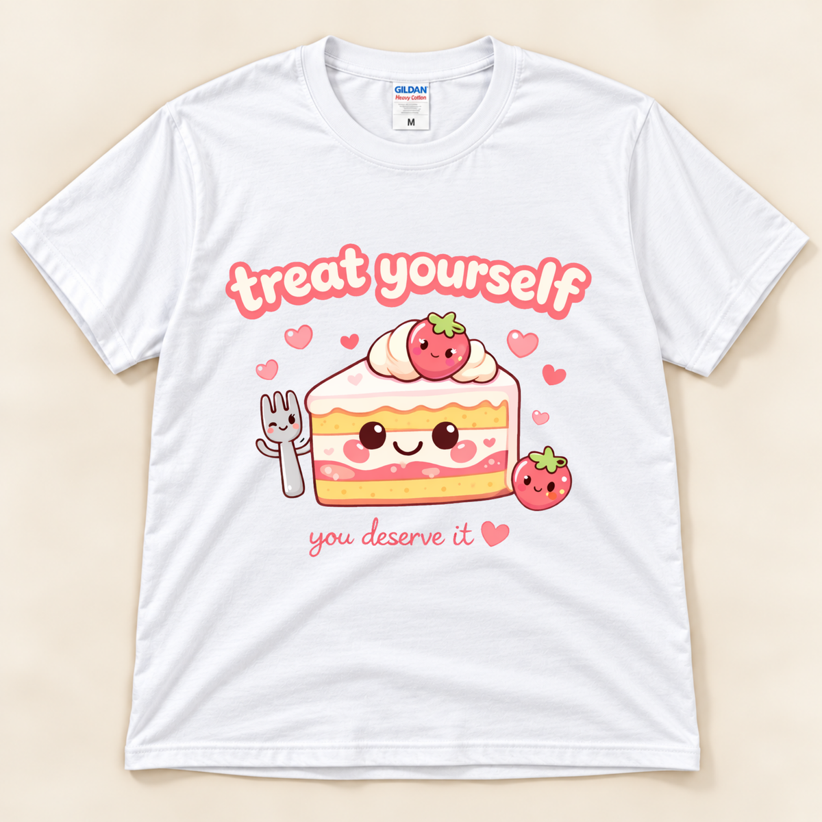 White Gildan 5000 strawberry cake graphic tee featuring a smiling kawaii cake slice, adorable fork, pink hearts and Treat Yourself You Deserve It lettering from New Chapter Tees, a California small business.