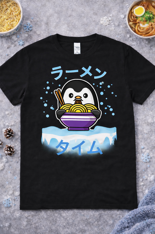 Kawaii penguin ramen graphic tee on black shirt featuring cute cartoon penguin eating noodles with chopsticks, Japanese ramen text, winter foodie anime design flatlay with snow and ramen bowls