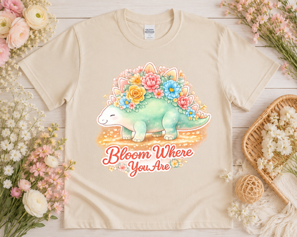 Bloom Where You Are floral dinosaur graphic tee on sand Gildan shirt with blush flowers and neutral cottagecore props