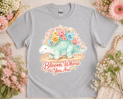 Bloom Where You Are floral dinosaur graphic tee on sport grey Gildan shirt with soft pink flower flatlay aesthetic