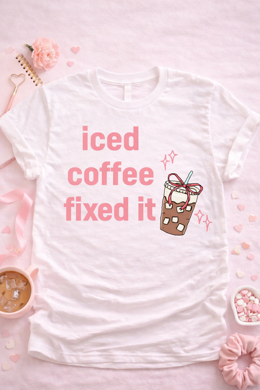 Iced coffee fixed it graphic tee on white shirt with cute iced coffee illustration and pink aesthetic lettering styled in soft flat lay for coffee lovers