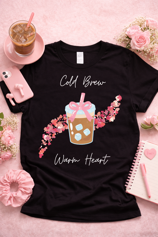 Black graphic t-shirt featuring kawaii iced coffee cup with pink bow and heart design, styled in aesthetic flat lay with roses, iced coffee, and soft pink accessories